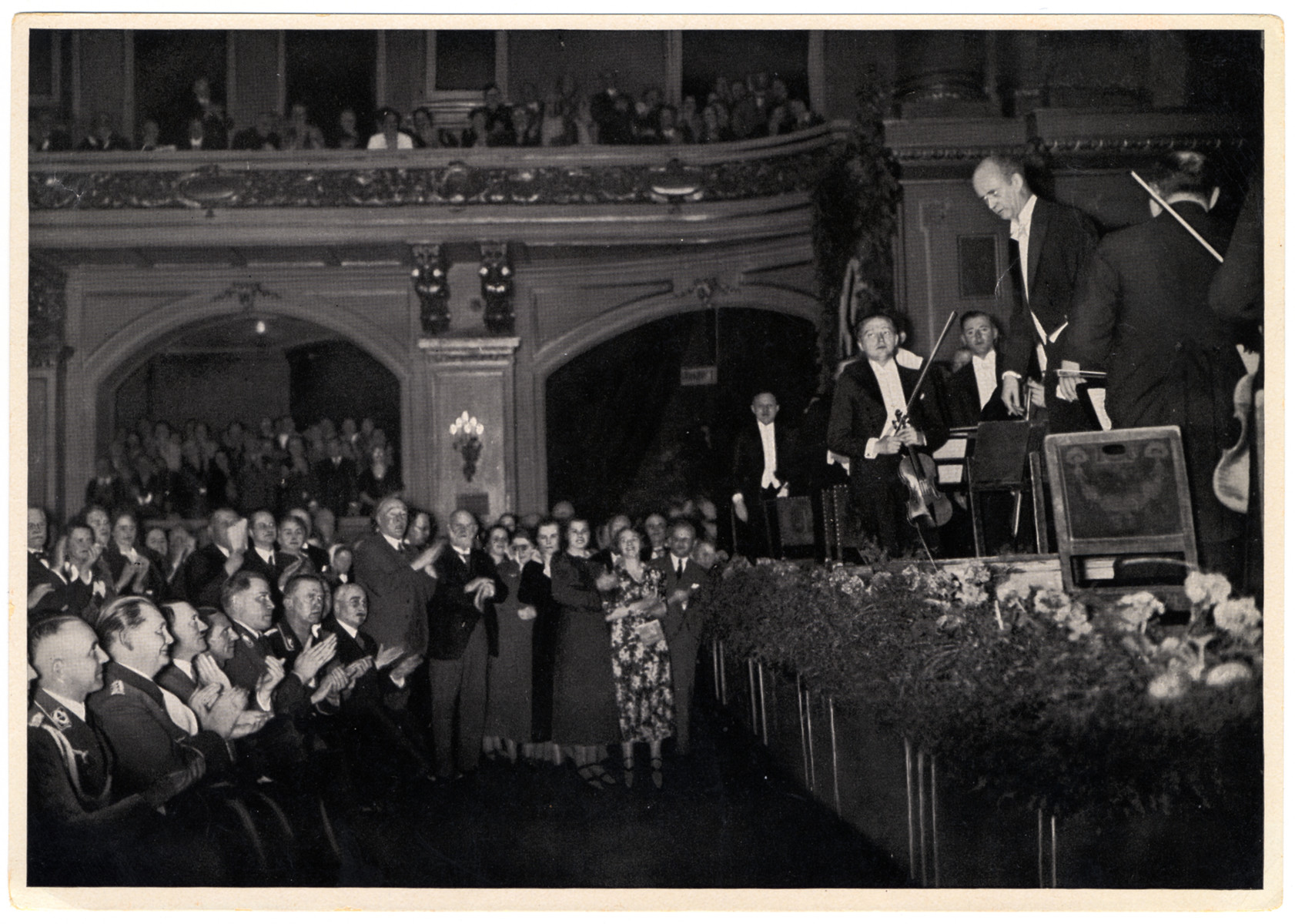 Hitler listens to the Berlin Philharmonic, directed by Wilhem Furtwangler. 

During the Great Depression, the Berlin Philharmonic was struggling economically until Josef Goebbels signed the orchestra and its members to a Nazi civil service contract in 1933. The orchestra became a part of the Strength through Joy (abreviated KdF) recreation organization that, when not performing mandatory concerts for Hitler, were part of the affordable entertainment offered to German citizens through the Ministry of Public Enlightenment and Propaganda. Members of the orchestra were completely exempt from all military service, which kept them playing until less than a month before the Red Army reached Berlin in 1945.