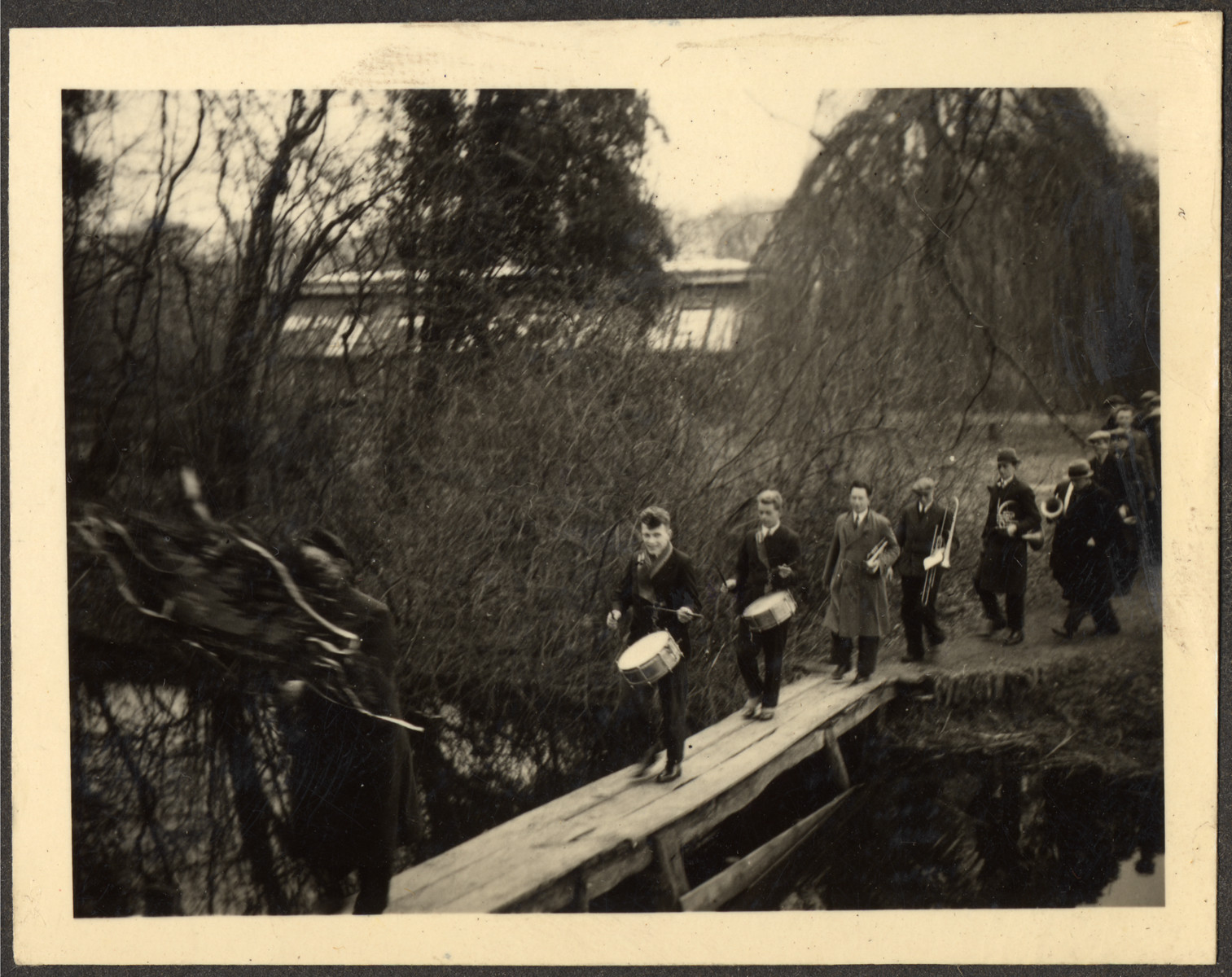 Students many of them German Jewish refugees, march with muscial instruments across a pedestrian bridge at a Quaker boarding school in Eerde.