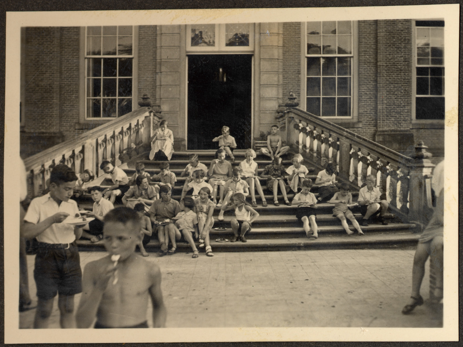 Children, many of them German Jewish refugees, relax on the steps of a Quaker boarding school in Eerde.