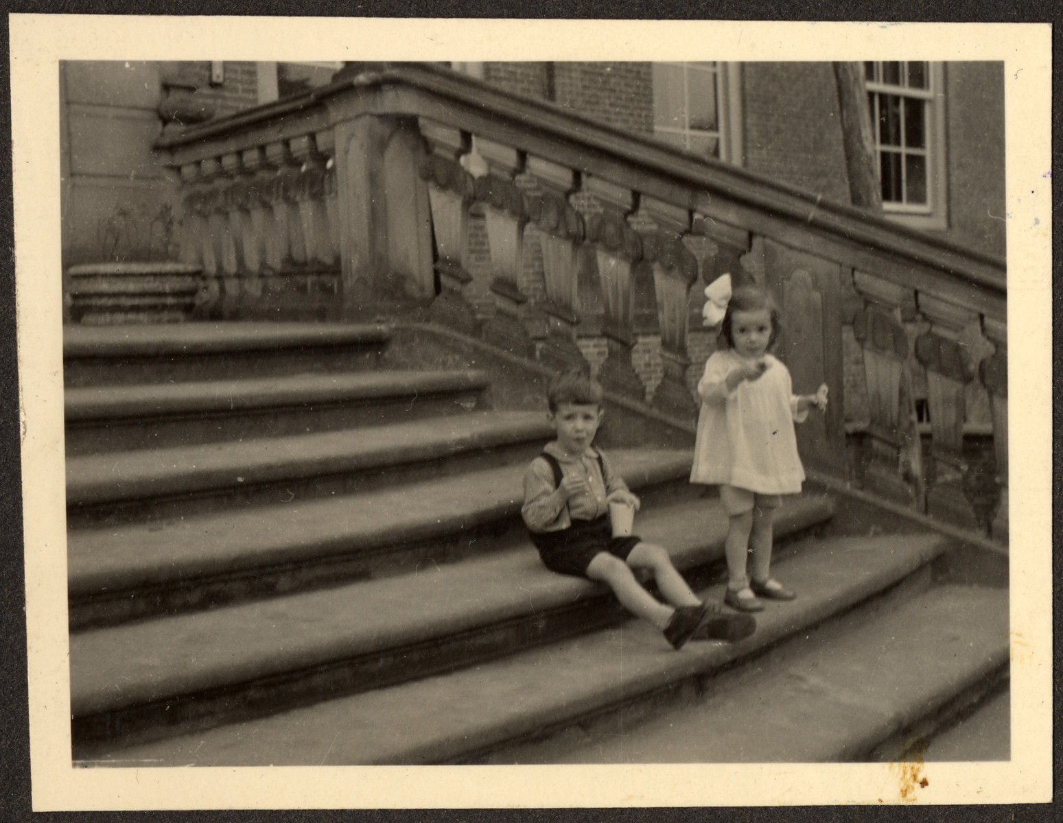 Two young children, probably German Jewish refugees, relax on the steps of a Quaker boarding school in Eerde.
