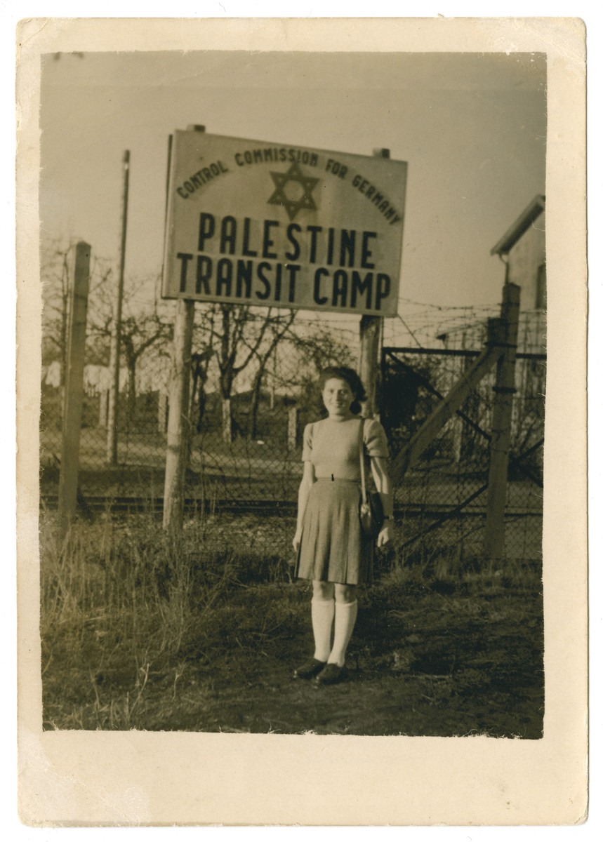 A young woman poses next to a sign for the Palestine Transit Camp.

The photograph is inscribed to my "best friend Rifka" from Feigi.