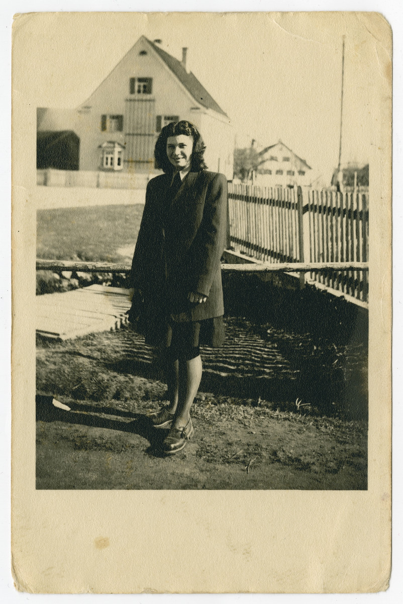 Malka Weiss (cousin of the donor) stands outside next to a fence in the Holzhausen displaced persons camp.