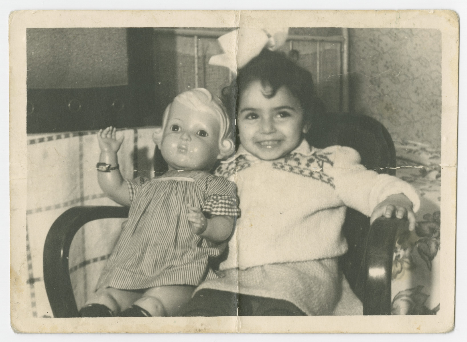 Ellen Zinger (daughter of Malka Lubochinski and Abram Zinger) sits in an armchair with her doll in the Bergen-Belsen displaced persons camp.