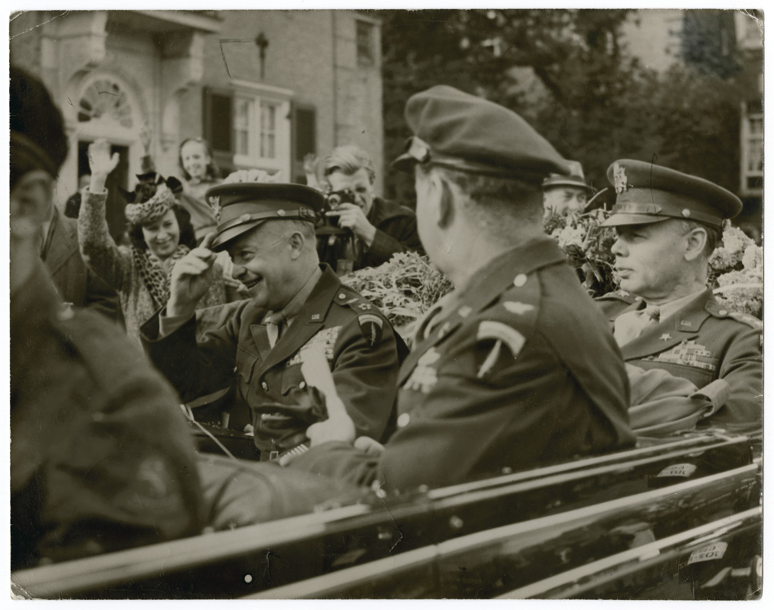 Gen. Eisenhower pays an official visit to The Netherlands after liberation.

Original caption reads:  General Eisenhower's visit to The Netherlands.  General Eisenhower leaving U.S. Ambassador Hornbeck's residence at the Hague.  In car Ike, Col. Griffith (with back to camera) and Lt. Gen. W.B.Smith.  (Girl waving immediately in front of General Eisenhower was girl who gave the General flowers and a kiss just before the General got in the car".