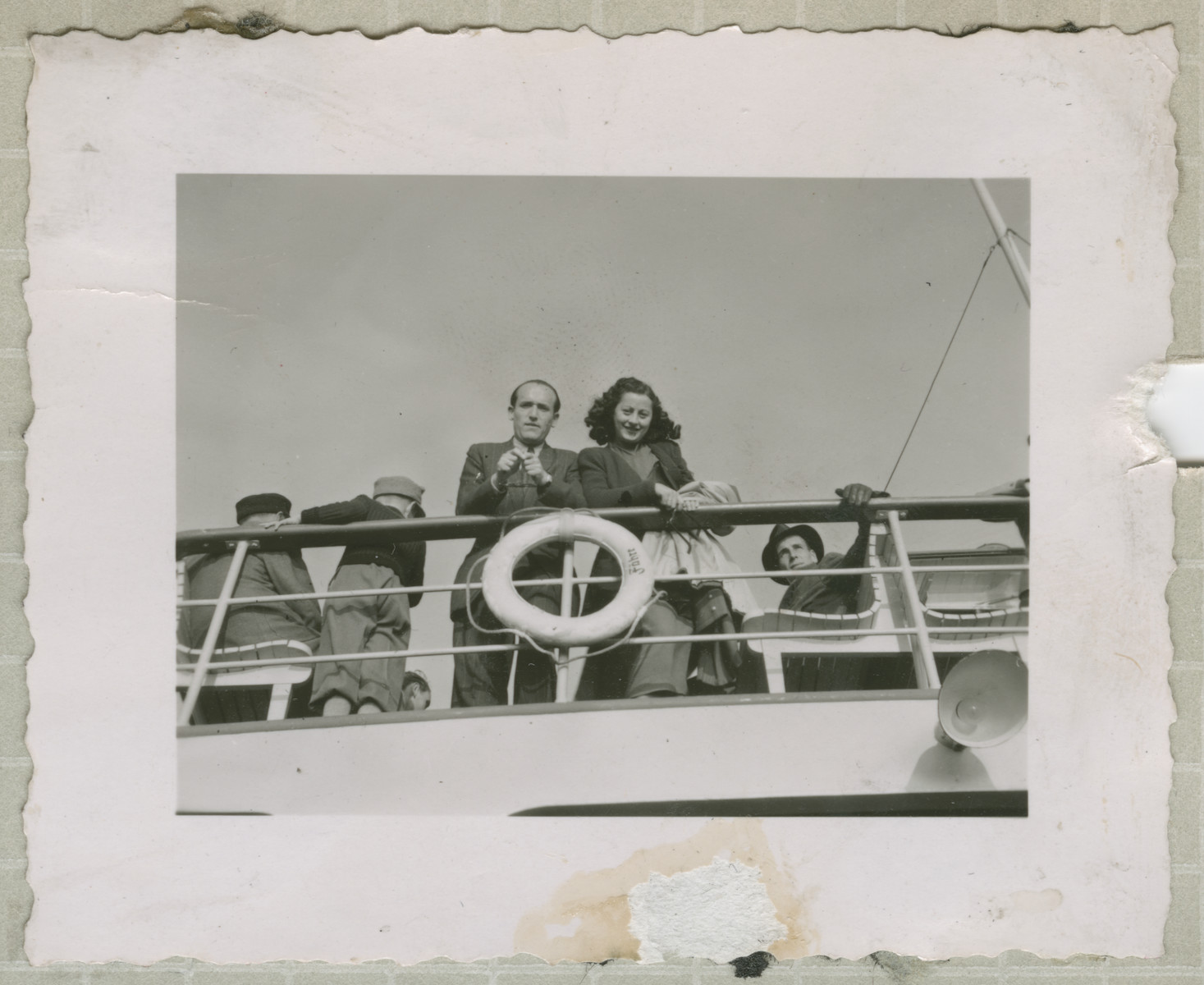 Immigrants to the United States stand on the deck of the Marine Flasher. 

In the center are Bronka Gutfreund and Mietek Amsterdam (later Max Fisch).