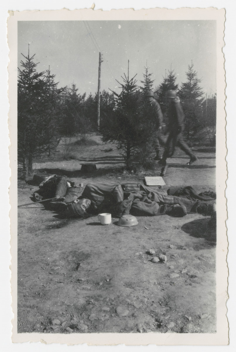 Two American soldiers lwalk by victims' corpses lying in an open field in the Ohrdruf concentration camp.