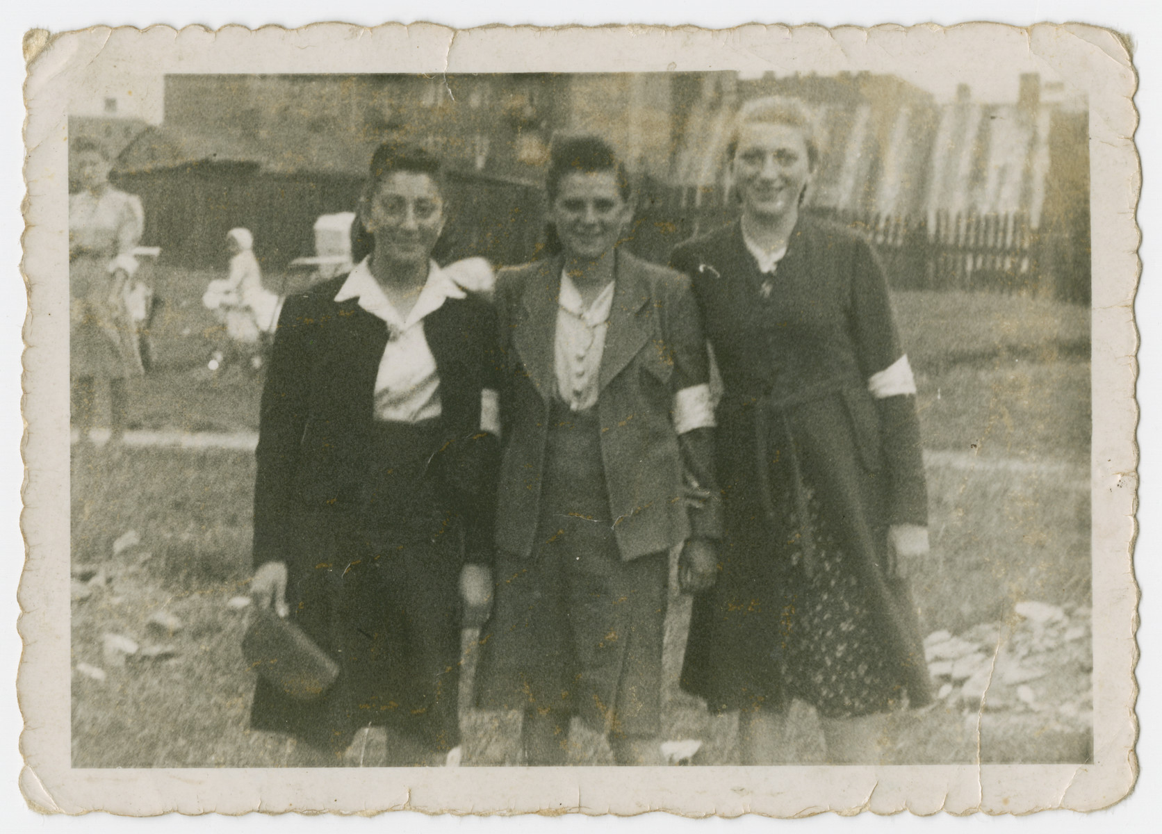 Three young women wearing armbands pose outside in the Sosnowiec ghetto.

Genya Rosenzweig (sister of David) is pictured in the center.