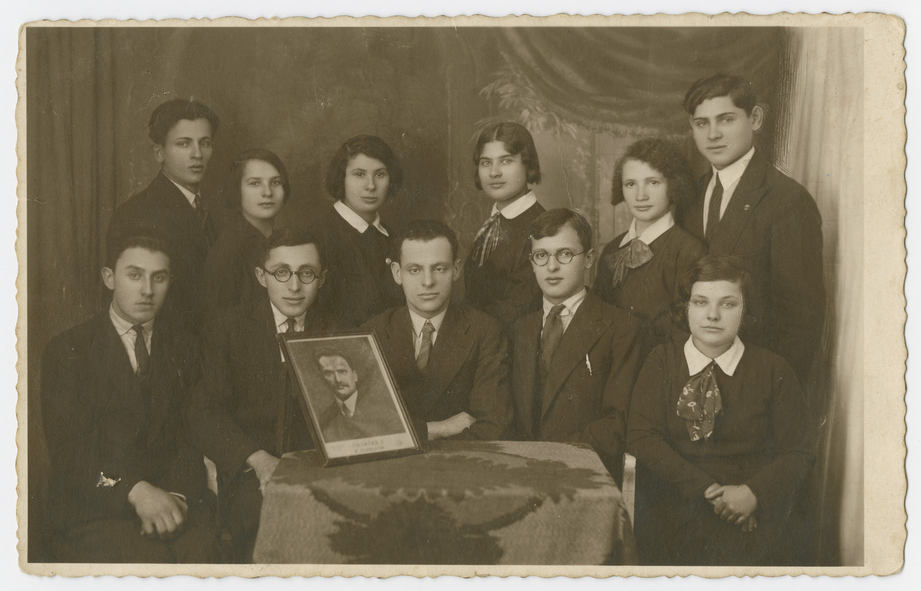 Group portrait of young men and women (possibly members of a youth organization) holding a portrait in prewar Sosnowiec.