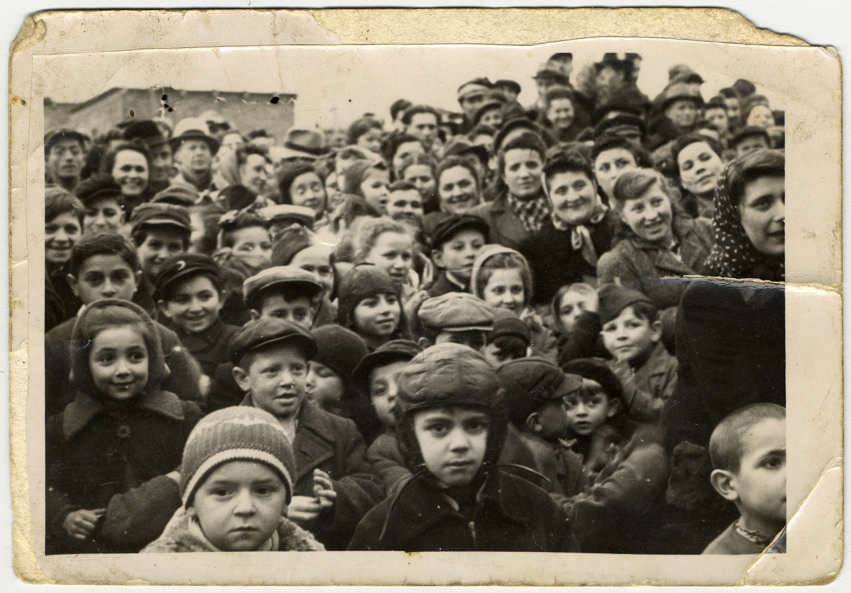 A large group of children and adults crowds together in the Zeilsheim displaced persons' camp.

Henik Minuskin is at the bottom, wearing a Russian pilot's hat.