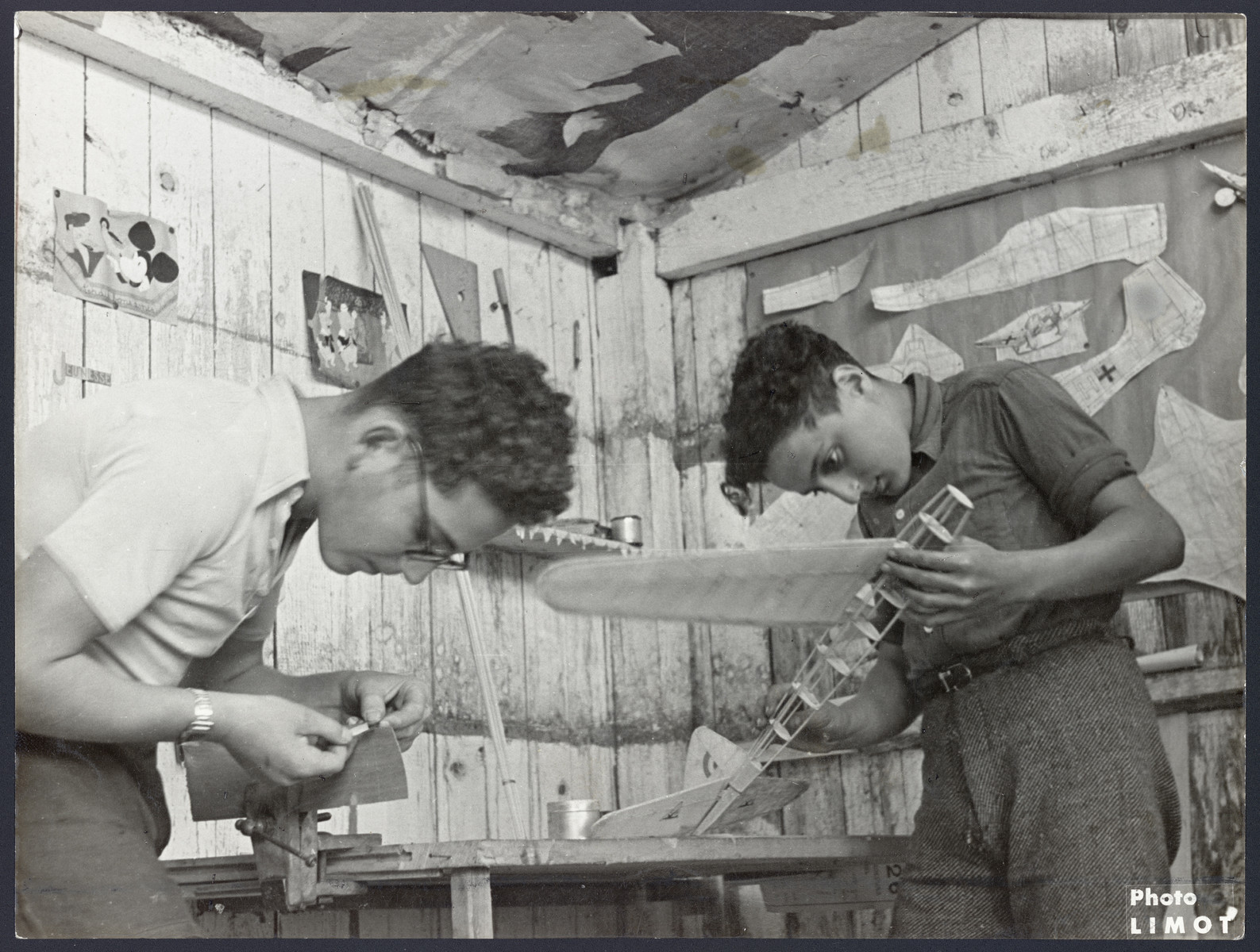Two teeange boys build wooden airplane models in a postwar OSE children's home in France.