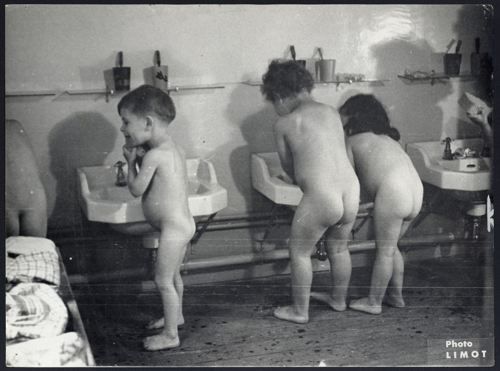 Young children in an OSE/JDC children's home wash up and brush their teeth.

The original caption reads "Its Fun to be Clean:  These French Jewish children who were hidden for years in caves and forests discover that running water and clean individual towels can be fun. These little ones who can scarcely remember home and family are now learning what decent living is like in a Joint Distribution Committee supported children's home near Paris.  Some 70,000 children receive J.D.C aid.  20,000 of them, for the most part orphans, are being cared for in 244 institutions which stretch from Brussels to Bucharest, from Paris to Prague.  In France alone there are 43 J.D.C. orphanages".