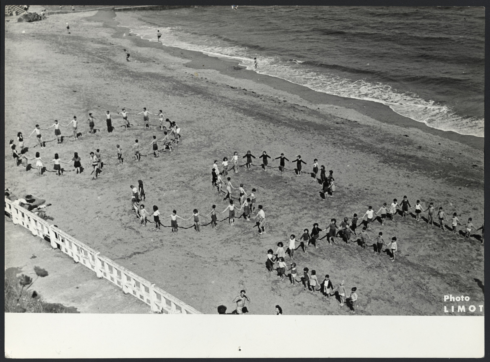 Children spell out the word "OSE" on the beach in Saint Quay.

The original caption reads "Vacation at the seaside".