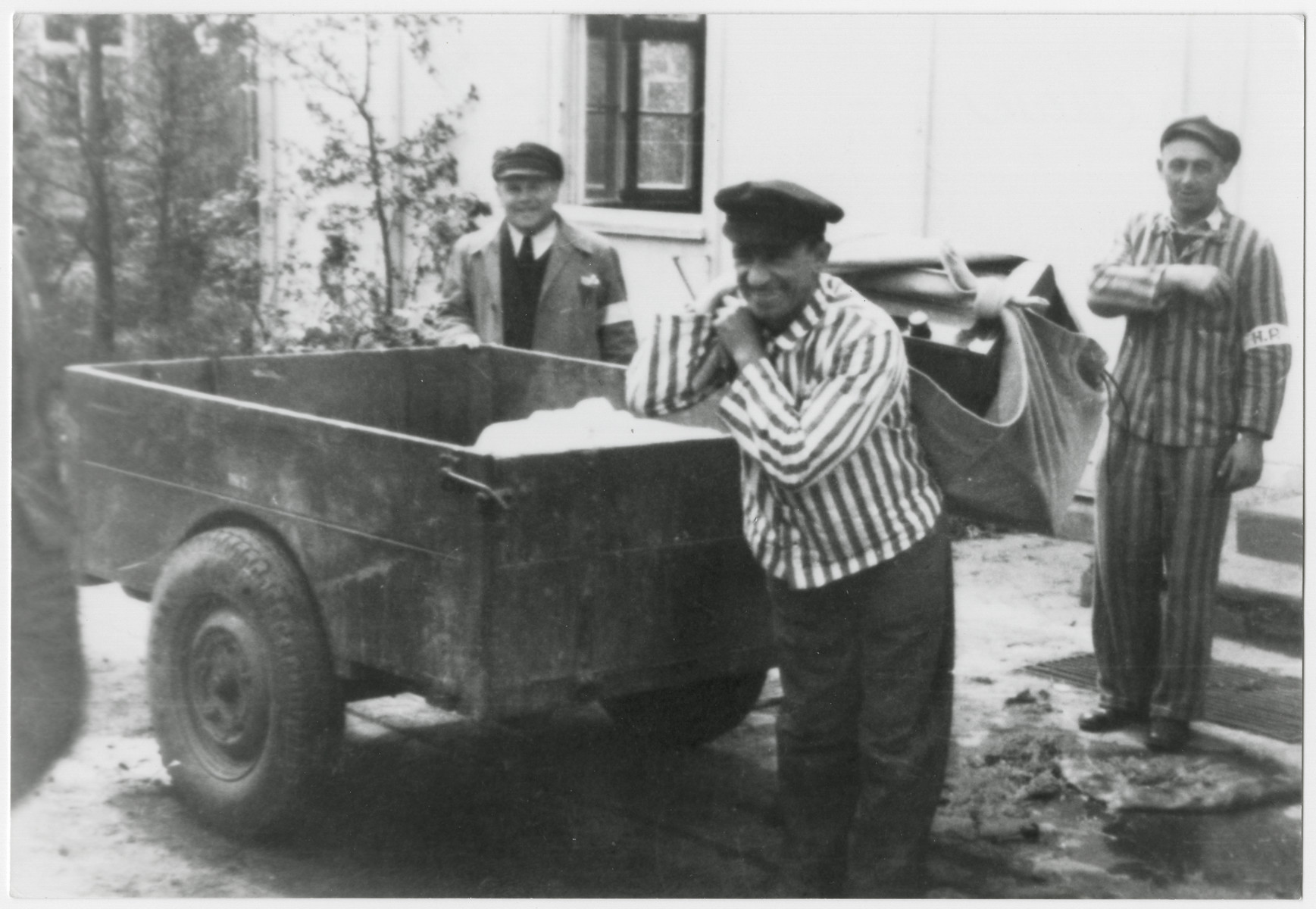 Survivors of the Dachau concentration camp haul electrical equipment in a sack.