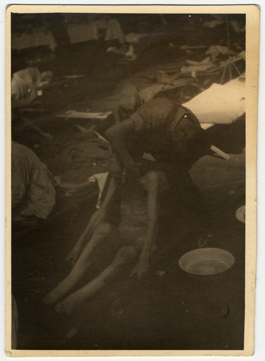 A German bathes a survivor at a makeshift infirmary inside of an airplane hanger.