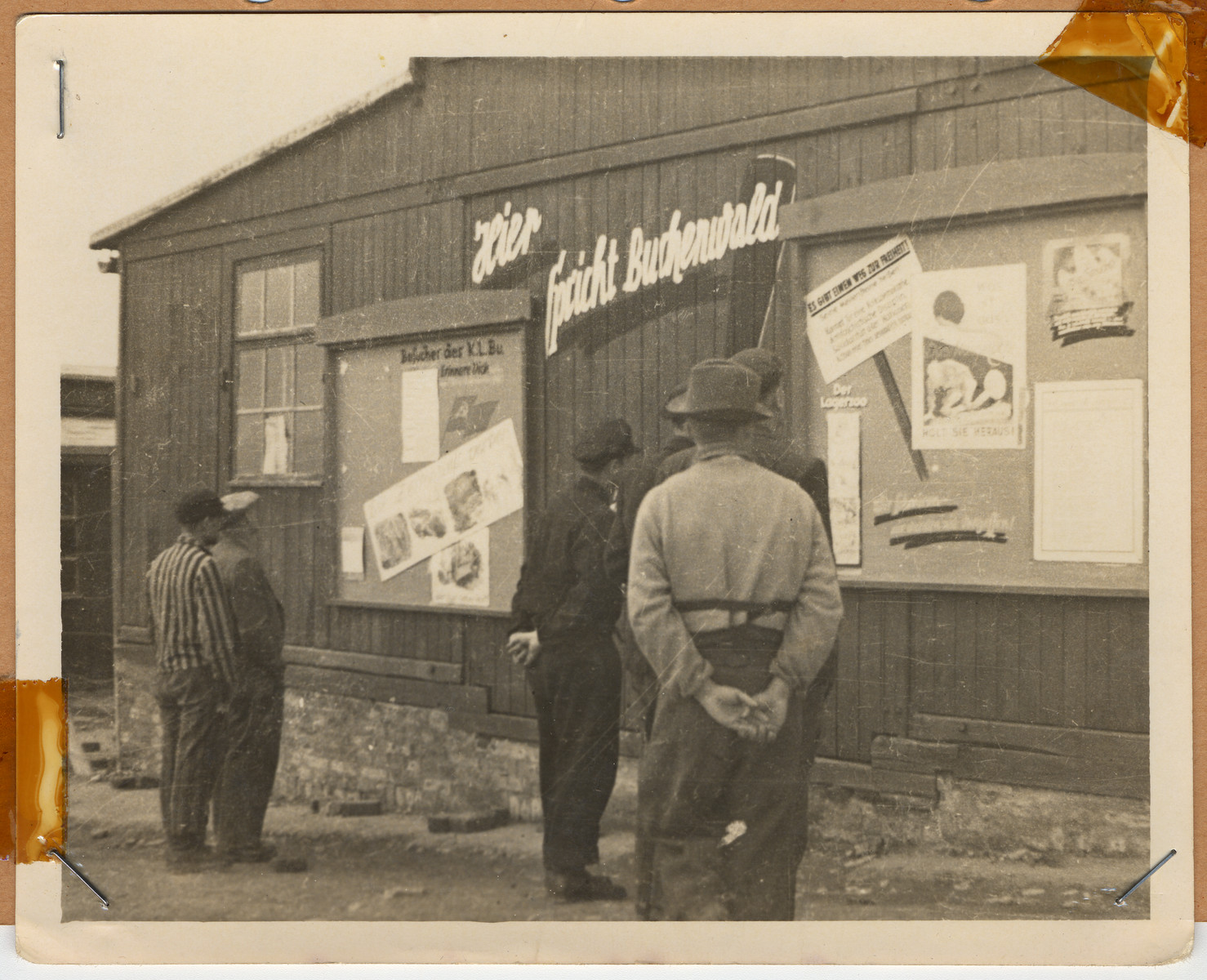 Survivors read signs posted on the side of a building in Buchenwald.

The lender's handwritten caption reads, "This was a Russian building."