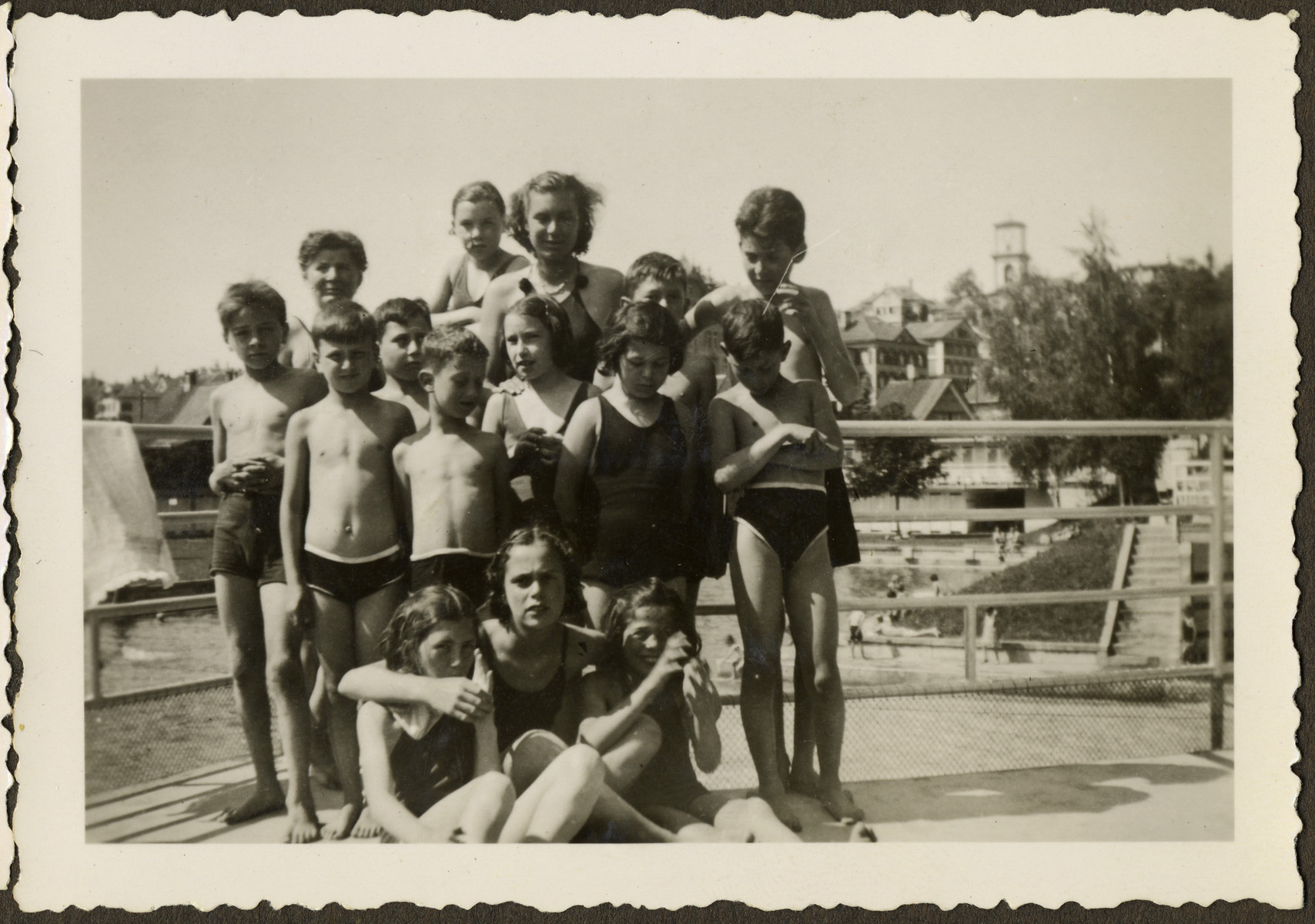 Group portrait of children in their bathing suits from the Heiden children's home in Switzerland visiting a public swimming pool.  All of the children had been on the Kasztner Transport.

Manny Mandel is standing first row on the right looking down.