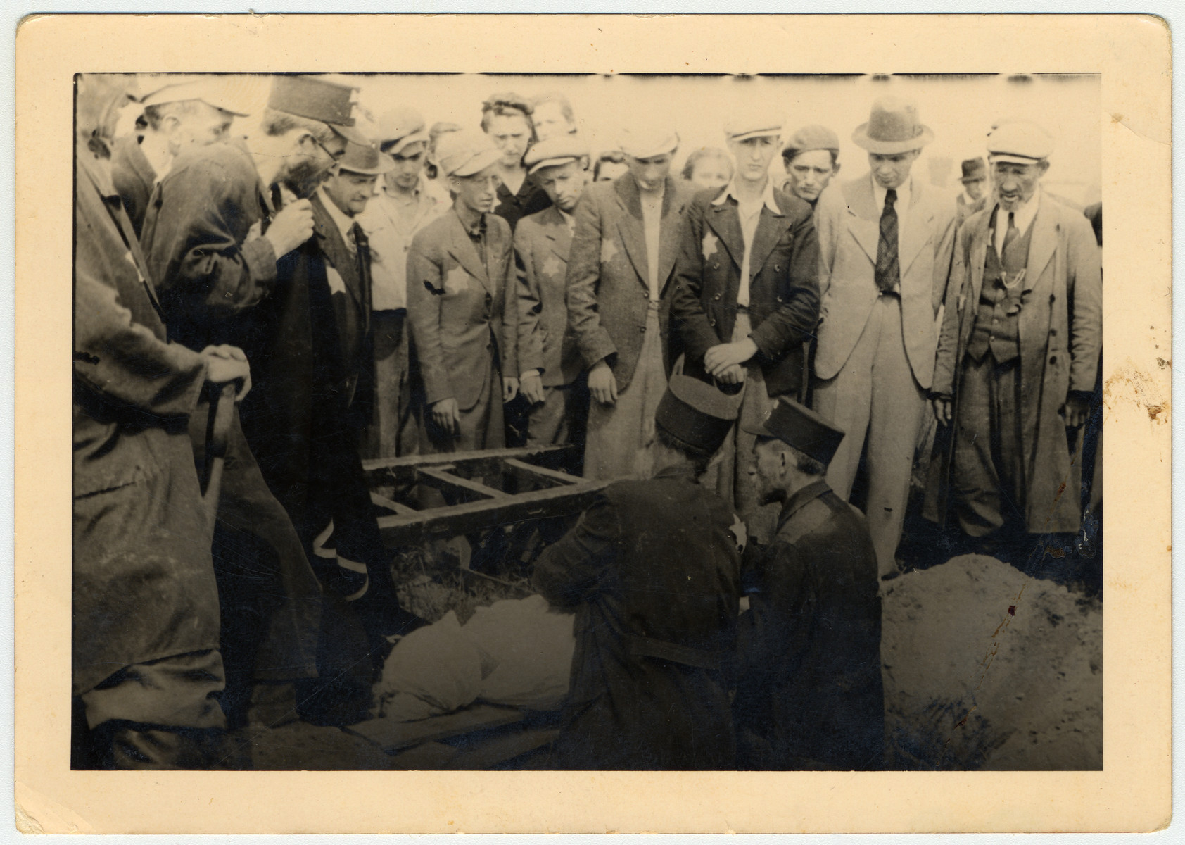 Jews gather by a graveside during a funeral of a girl killed by a lightning strike in the Lodz ghetto.

Standing third from right is Henryk Bergman and next to him, second from right, is Kaufman.