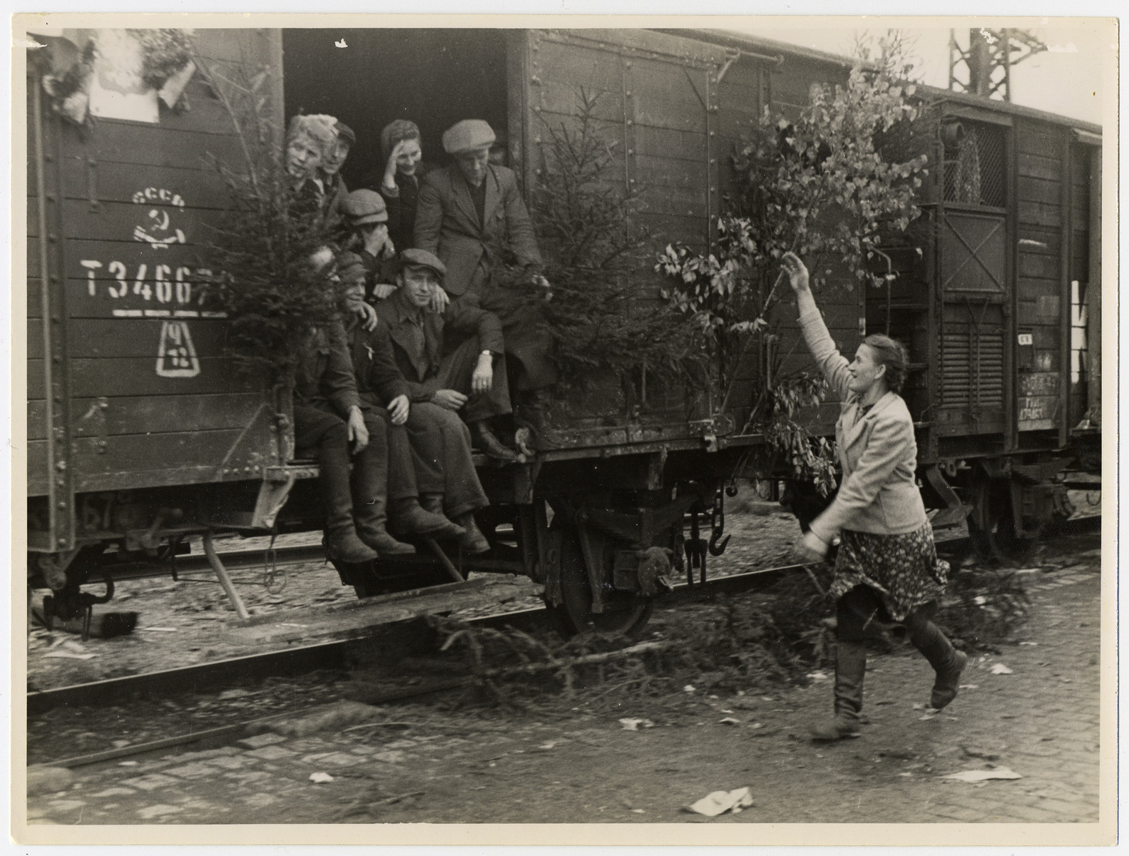 A woman waves farewell to displaced persons leaving Germany on a decorated U.S. Army train.