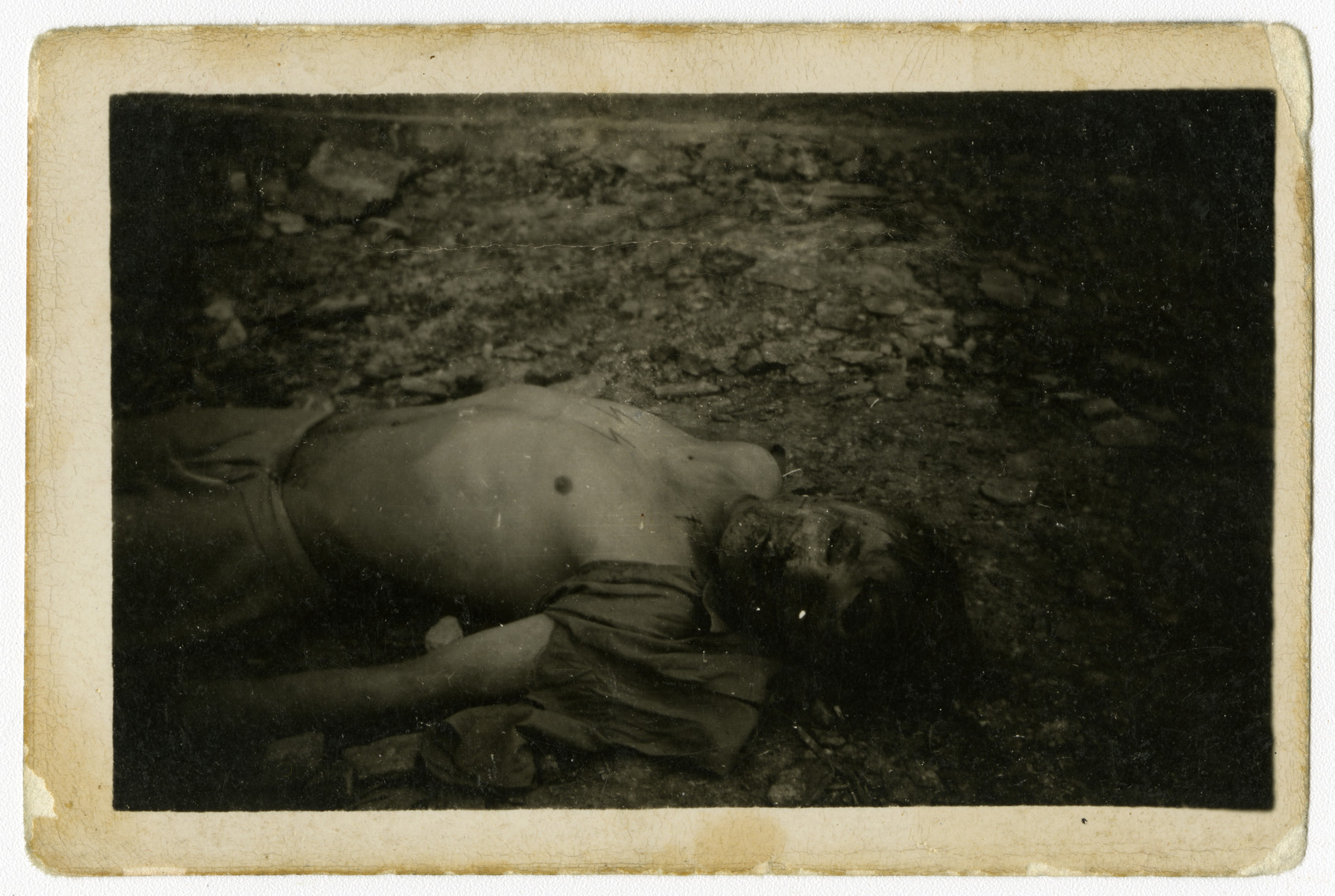 Close-up of the corpse of a former SS guard; his shirt has been torn off exposing his SS tattoo.