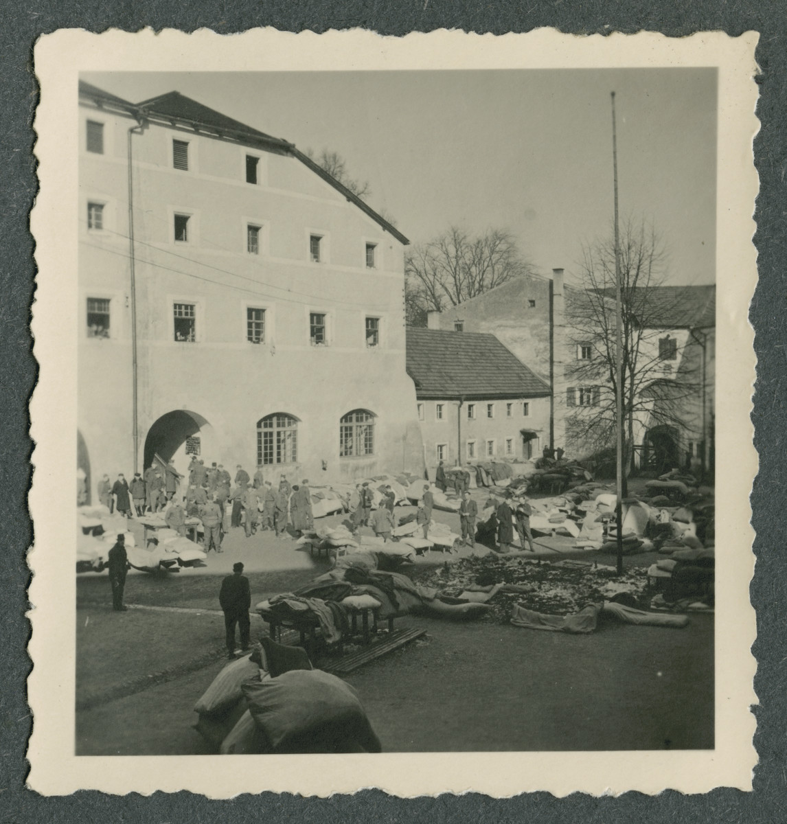 Prisoners either sort or open up bedding and bundles in the courtyard of Tittmoning castle.