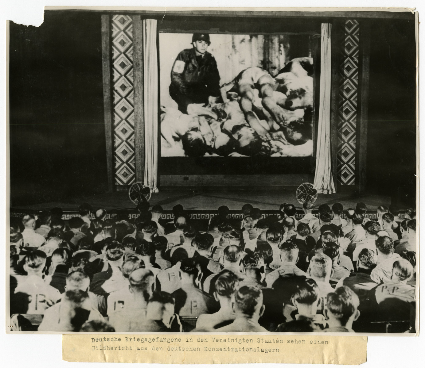 German soldiers are forced watch an atrocity film about concentration camps

Original caption reads: Deutsche Kriegsgefangene in den Vereinigten Staaten sehen einen Bildbericht aus den deutschen Konzentrationslagern

[German prisoners of war held in an American camp watch a film about German concentration camps.]