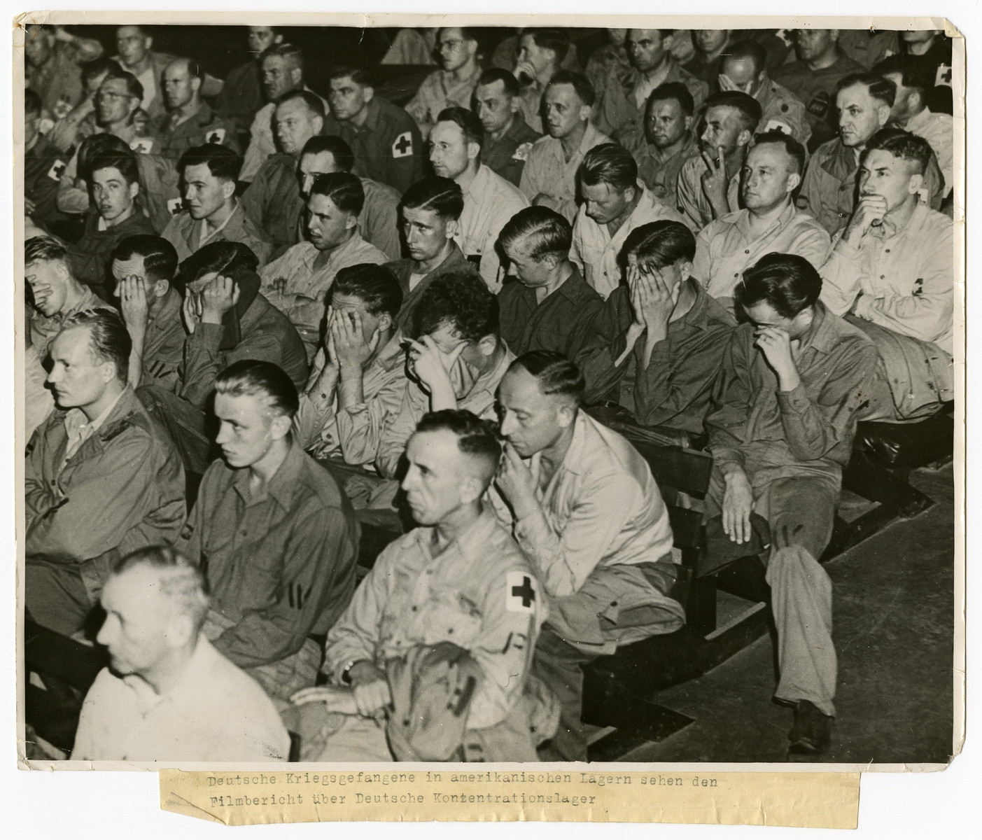 German prisoners of war are forced to watch an atrocity  film on German concentration camps.

Original caption reads: 
Deutsche Kriegsgefangene in amerikanischen Lagern sehen den Filmbericht über Deutsche Konzentrationslager 

[German prisoners of war held in an American camp watch a film about German concentration camps.]