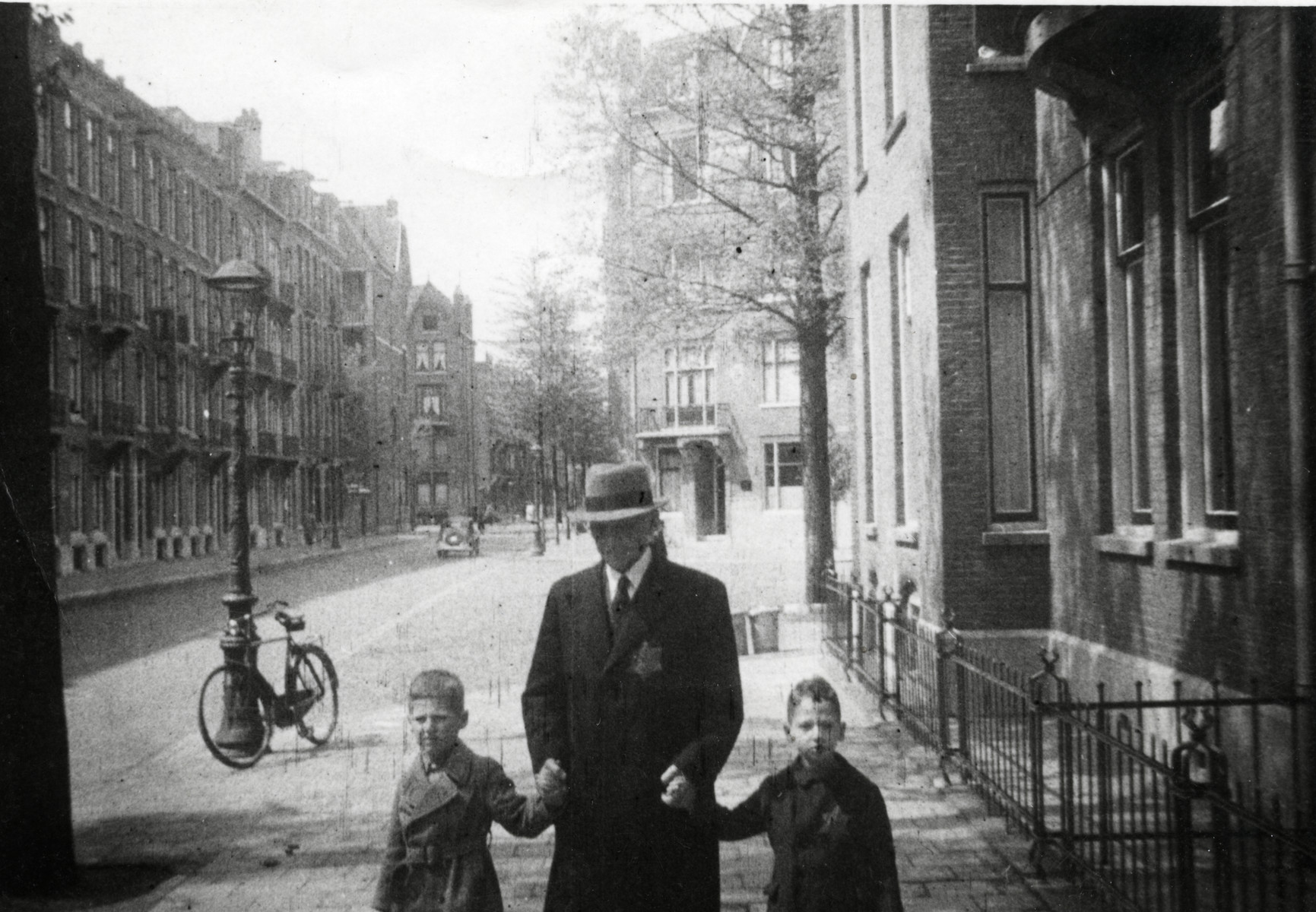 Hartog Kisch walks down the street with his two grandsons Eldad and Hanan .

The grandfather and Eldad are both wearing Jewish stars.  Eldad was not required to wear a Jewish star but wanted to anyhow.