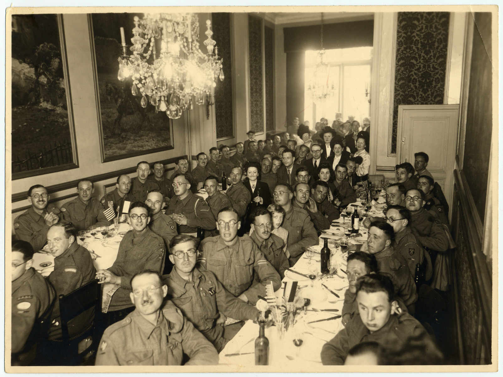 Members of the Jewish Brigade gather at set tables for a festive meal.

Fela Perelman is pictured in the middle.