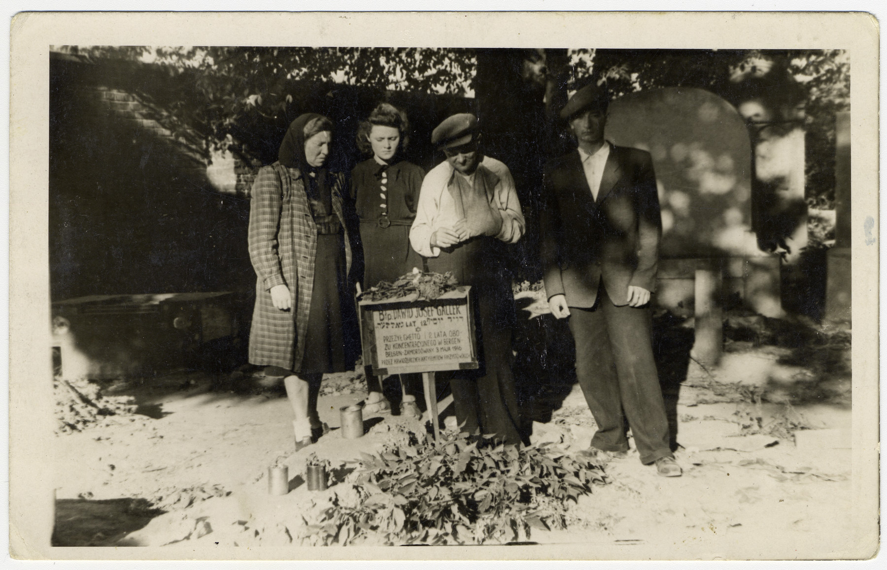 The Galler family stands by the grave of Jews killed in a postwar attack on members of the Zionist group Gordonia outside of Krakow.

Among those killed was Yosef Galler.  Pictured are Maria Galler (his mother), Renna Galler (his sister) and Izrael Galler (his father).  The man on the far right is unidentified.  The family survived Bergen-Belsen on Argentinian papers and were liberated on the train in Fallersleben.