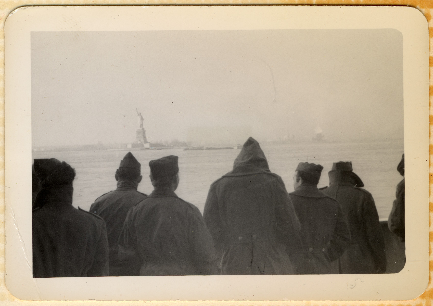 American GIs stand on the deck of their troop ship and look at the Statue of Liberty as they pull into NY harbor on their return home from World War II.