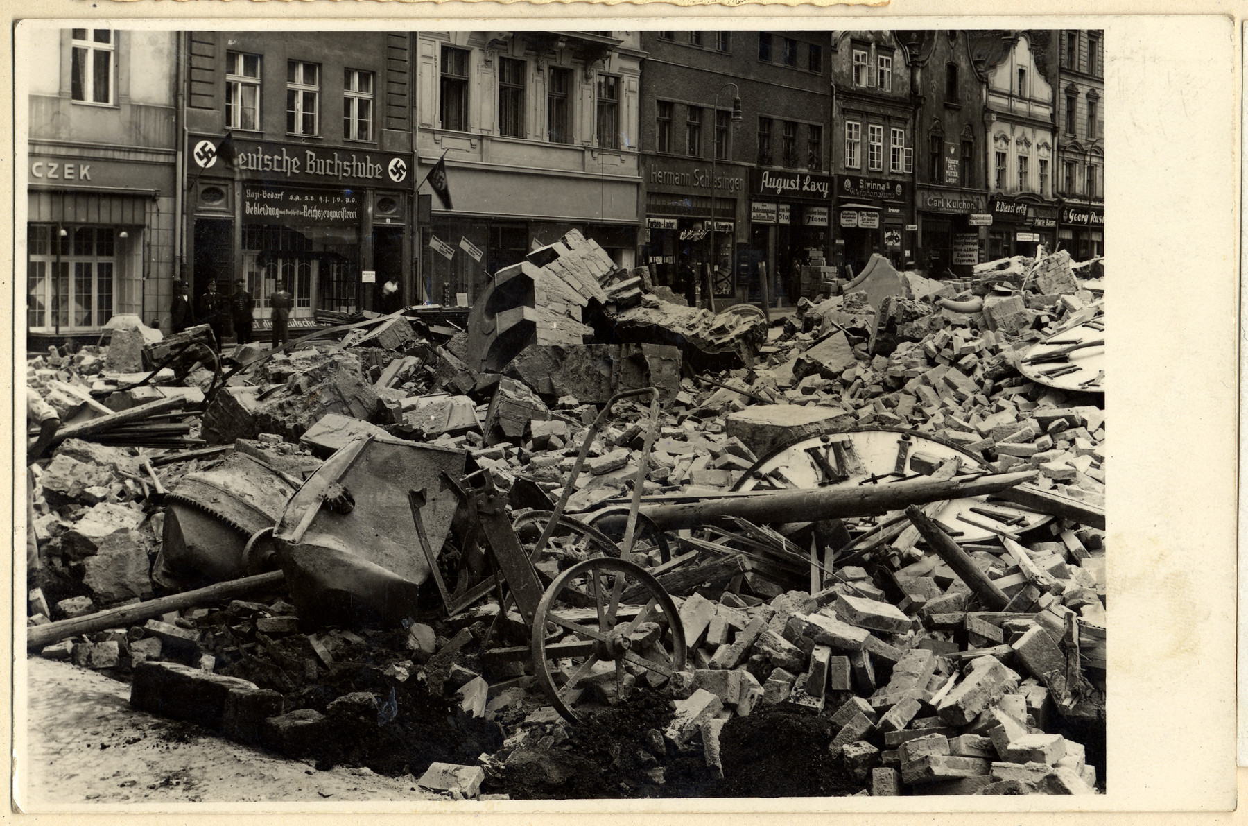 View of a major artery in Oppeln after the collapse of a clock tower.  The shop in the background is a Nazified book store.