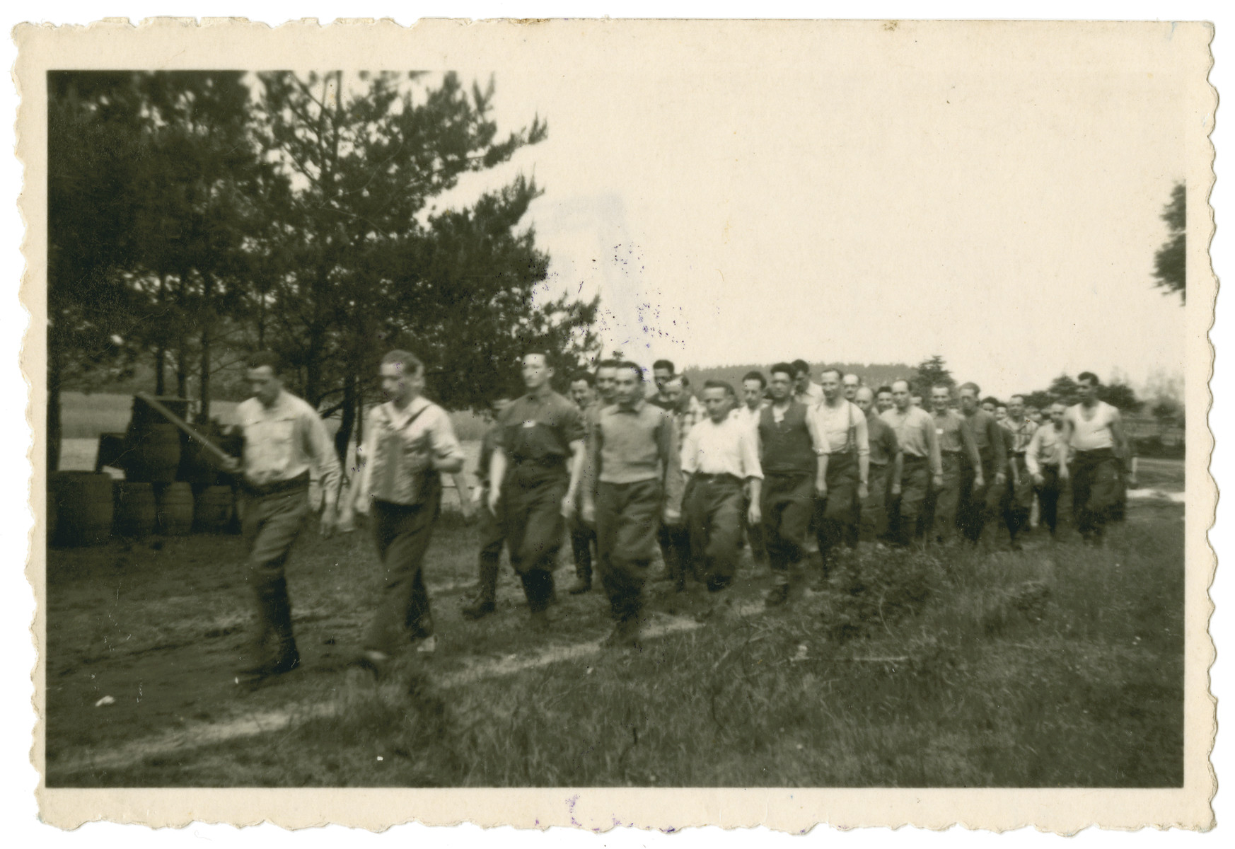 Belgian POWs march through Stalag 10 C led by one man playing accordion and another holding a violin.