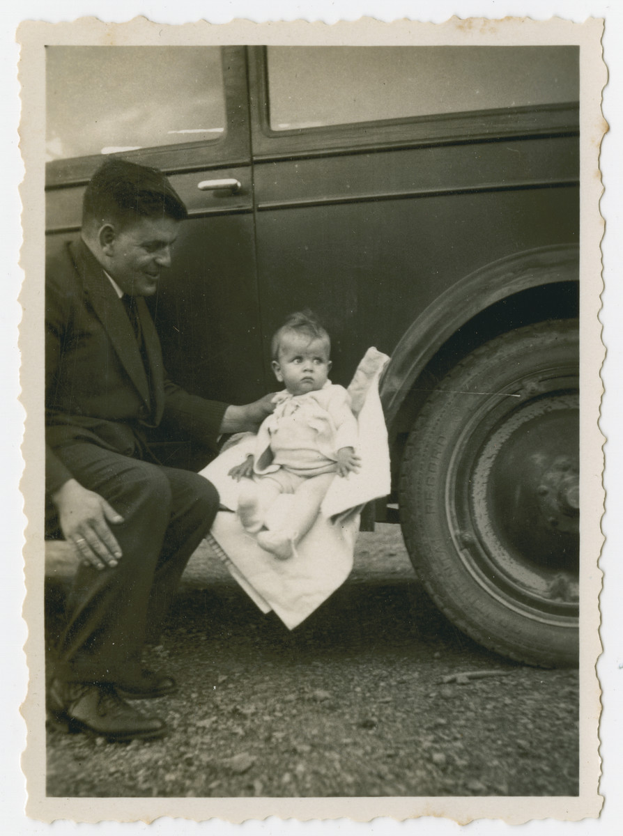 Julius Gutheim sits next to his daughter on the running board of their automobile.