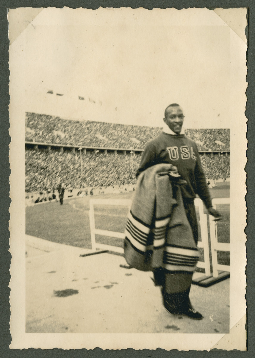 Gold-medalist Jesse Owens carrying a blanket  while inside the Olympic stadium in Berlin.

The original caption reads: "Jessie Owens, the fastest man in the world."