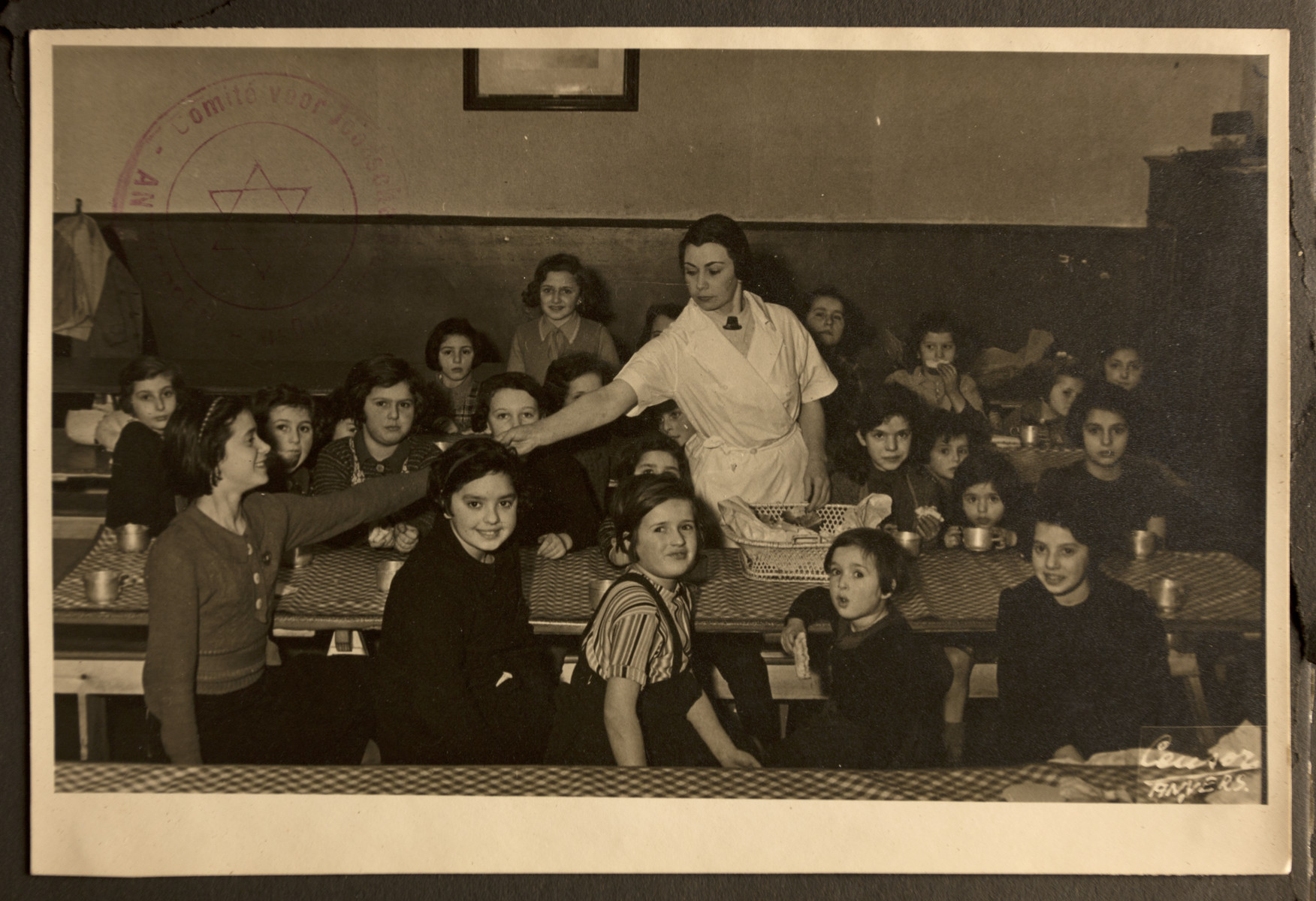 A woman serves refugee children in the dining room of the Jewish Refugee Aid Committee of Antwerp.