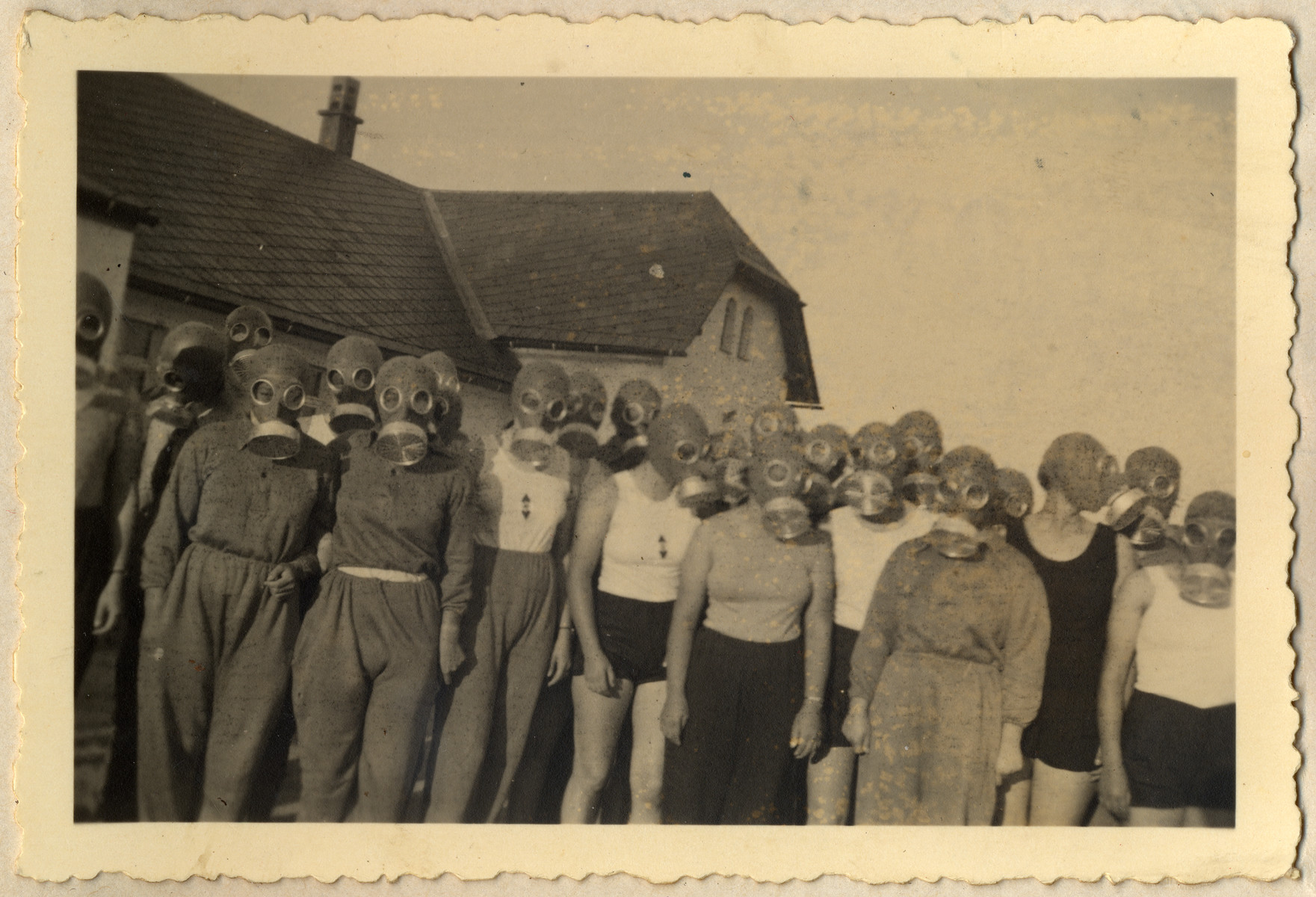 Young German women in the Reich Labor Service are photographed wearing gasmasks during an air raid drill (some wear BdM shirts).