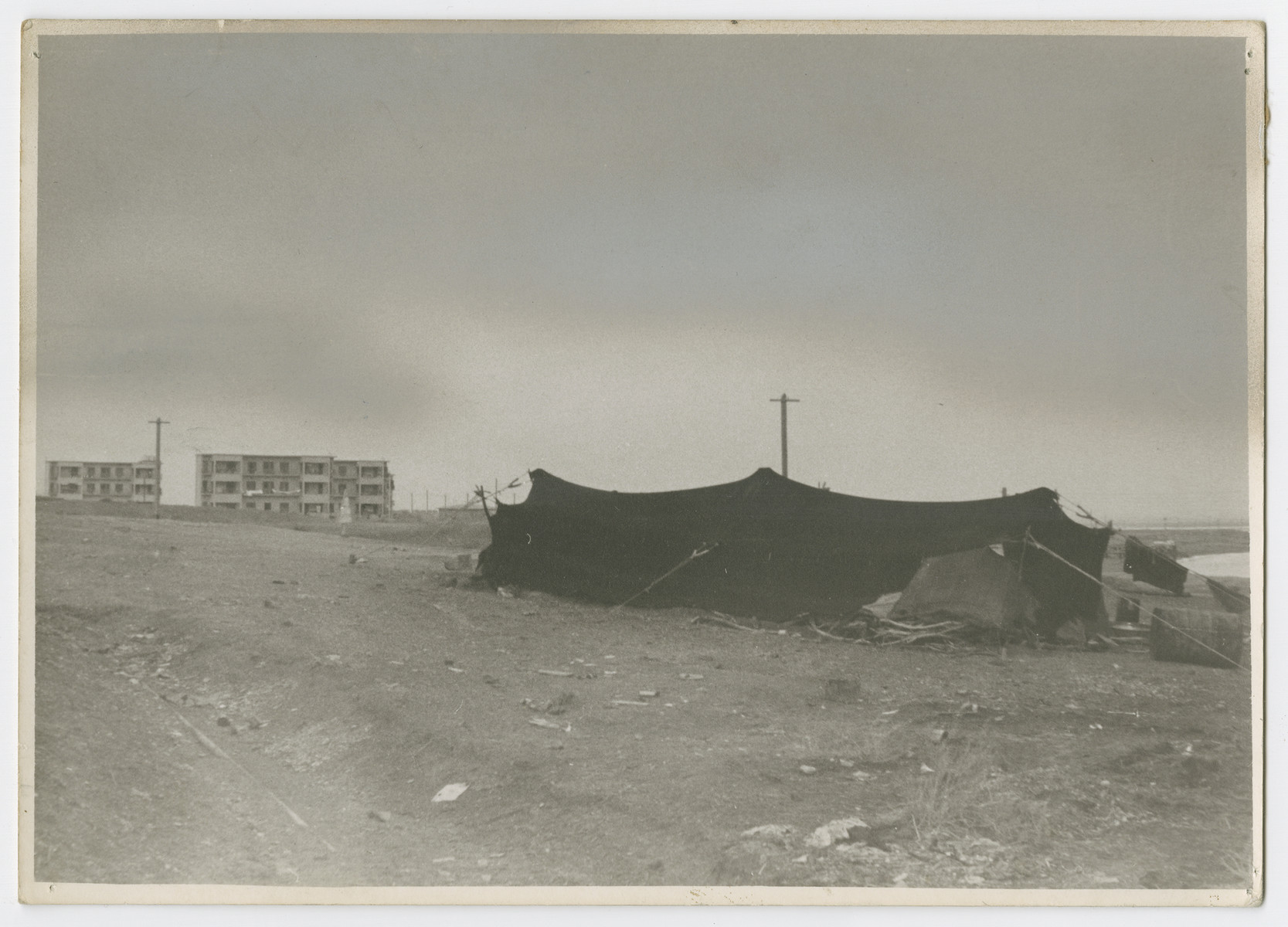 View of a Bedouin tent and a Jewish housing project near the banks of the Dead Sea. 

Photograph is used on page 188 of Robert Gessner's "Some of My Best Friends are Jews." The pencil inscription on the back of the photograph reads, "Dead Sea with PJ and Arb workers."