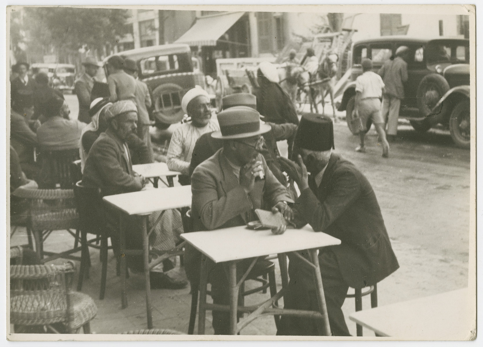 Men sit at sidewalk cafes in Tel Aviv and negotiate land purchases.

Photograph is used on page 182 of Robert Gessner's "Some of My Best Friends are Jews." The pencil inscription on the back of the photograph reads, "Bartering for land."