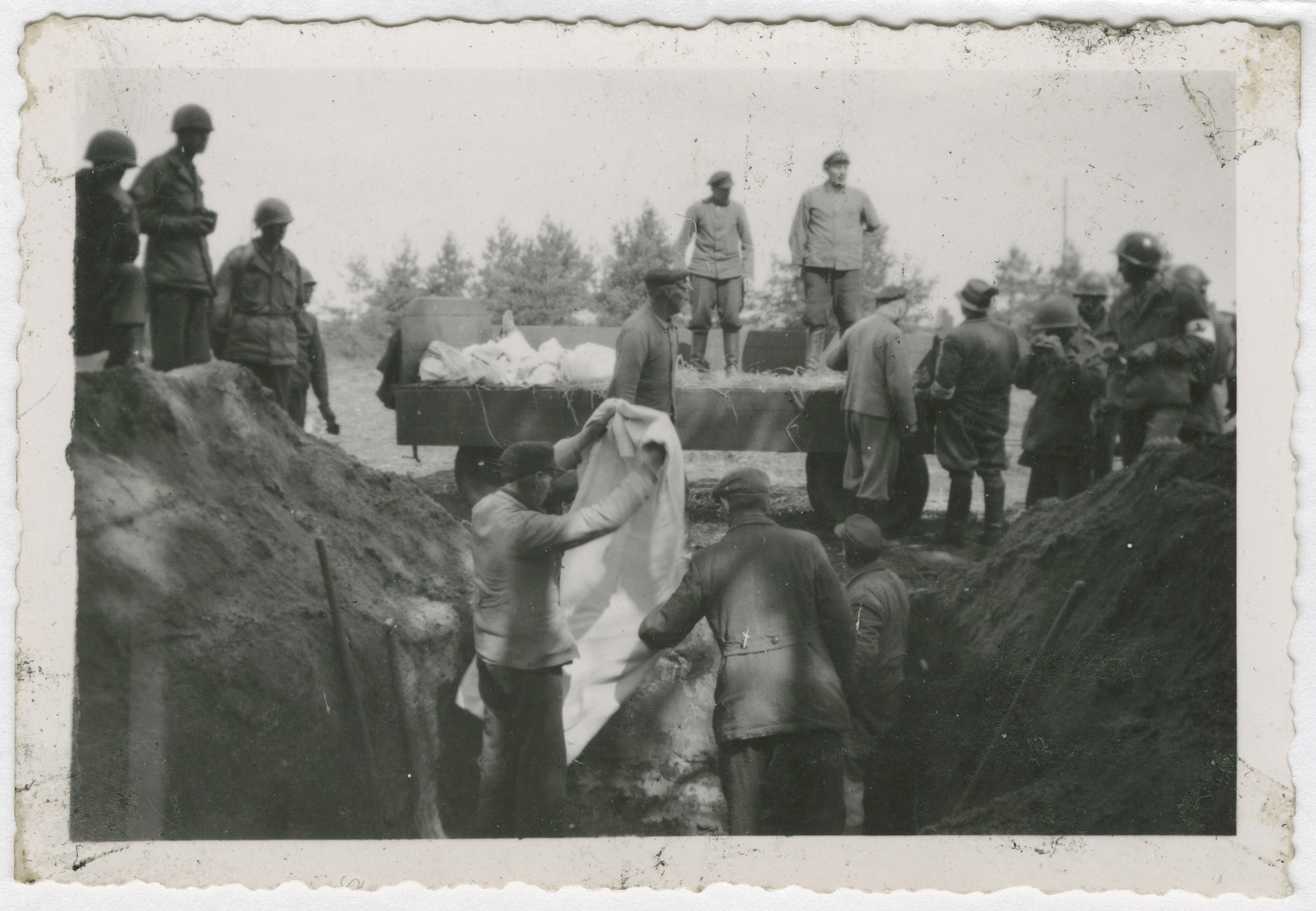American troops supervise the exhumation for reburial of corpses from a mass grave in either the Buchenwald or Woebbelin concentration camp.