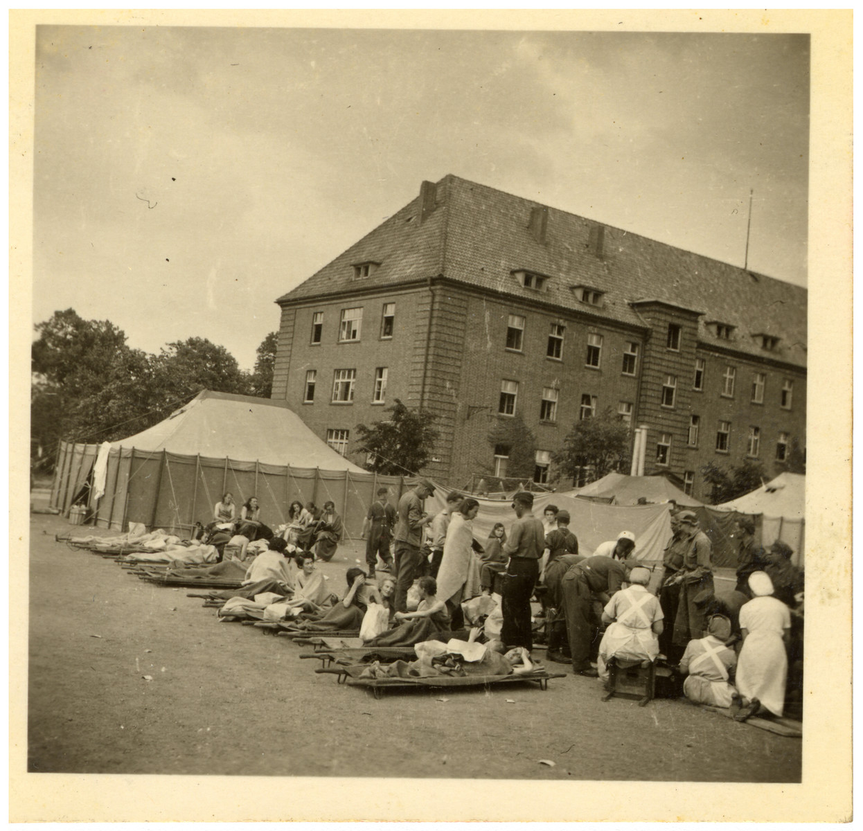 A group of women rests on stretchers and chairs while doctors and nurses attend to another group of women behind them.