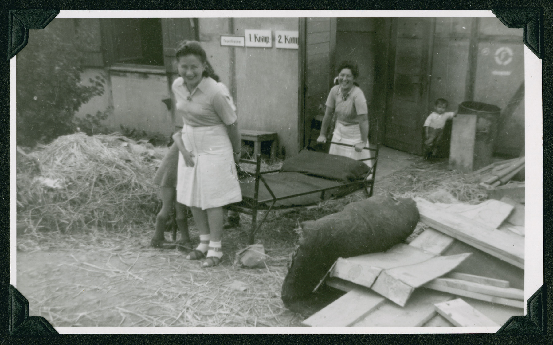 Two women carry a bed past a pile of lumber during the clean-up of the Ziegenhain displaced persons camp in order to make it liveable.

The original caption reads: "What confronted the Jewish Displaced Persons when they were brought to Ziegenhain."