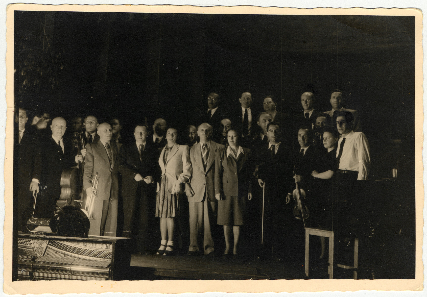 Performance of the Ex-Concentration Camp Orchestra conducted by Leonard Bernstein.

[Bernstein conducted two concerts the same day - -a matinee in Feldafing followed by an evening concert in Landsberg.  It is unclear in which camp this photo was taken.]

Pictured are Leonard Bernstein (far right), Fania Durmashkin (to his left), Max Beker (fourth from the right) and Henia Durmashkin (seventh from the right).