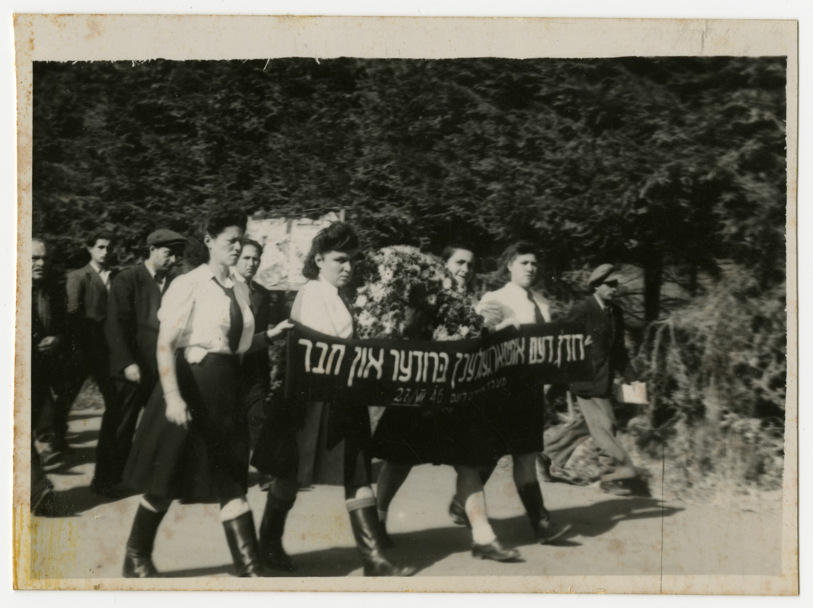 Women march in a funeral procession carrying a banner in memory of their "brother and friend"

This is possibly the funeral for David Kabesicki.  Among those pictured are Rifka Krasner (second from the left) and Jenta Szapiro (third from the left).