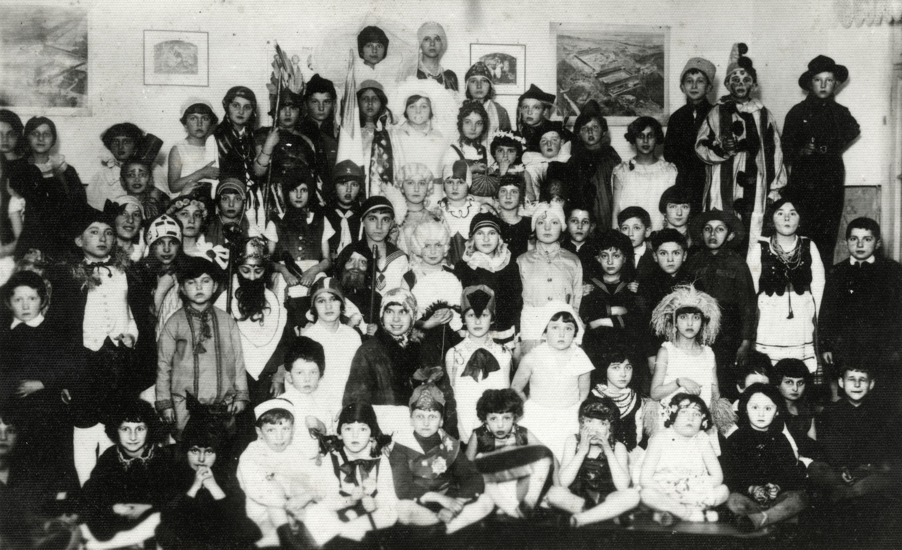 Children in the Humanistic school in Lublin, Poland pose for a group portrait in their Purim costumes.

Among those pictured is Yocheved Fryd dressed as Rebecca in a head scarf.