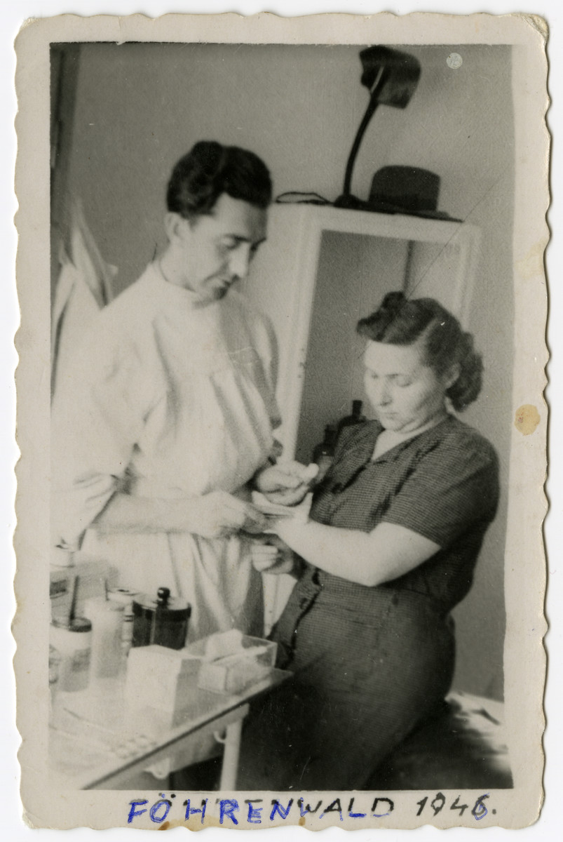 A woman receives medical treatment in the Foehrenwald displaced persons camp.

Pictured are Dr. Filo Mantel and a nurse [name unknown].