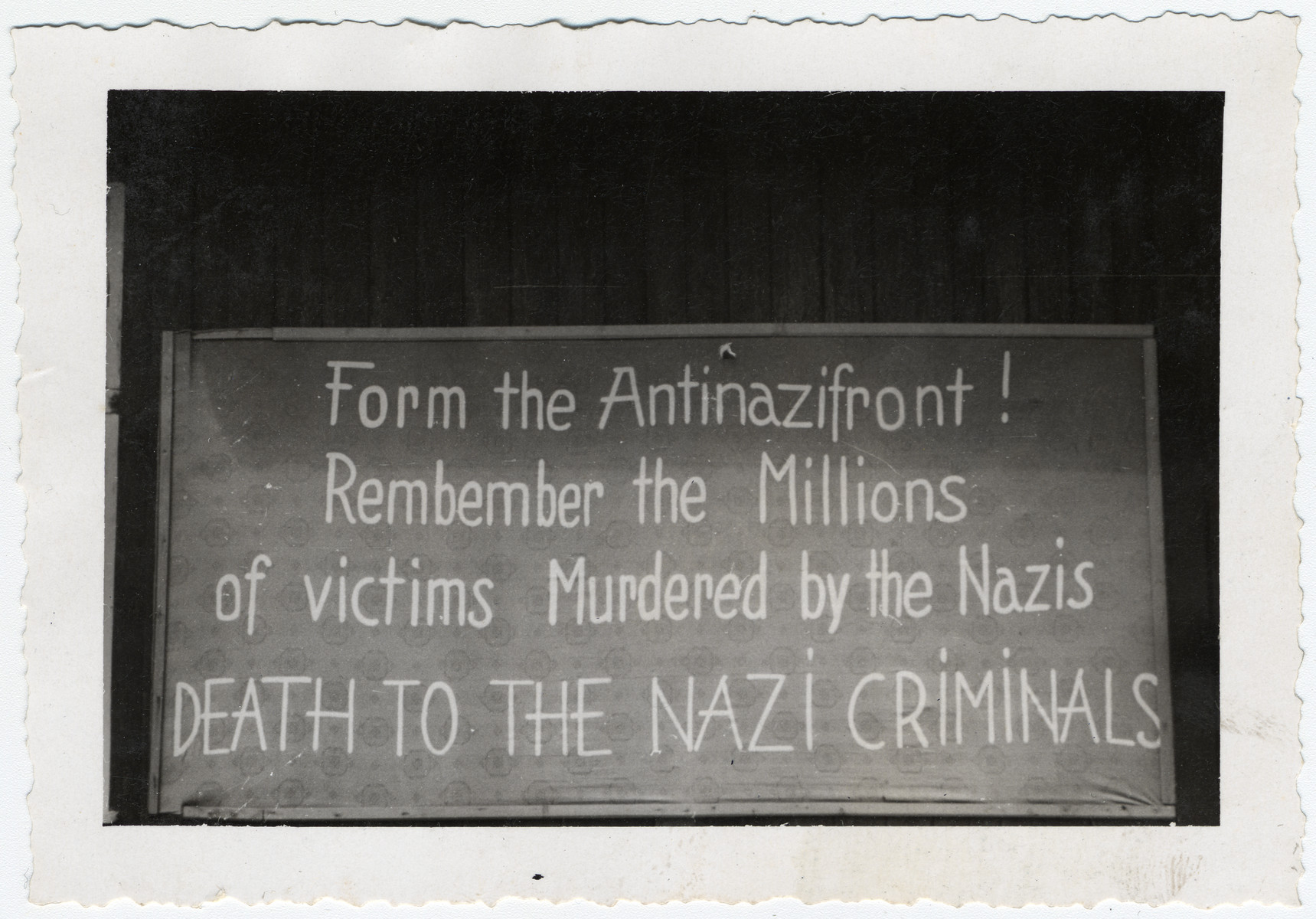 A sign posted [probably in Buchenwald] that says, "Form the Antinazifront! Remember the Millions of victims Murdered by the Nazis/ DEATH TO THE NAZI CRIMINALS."