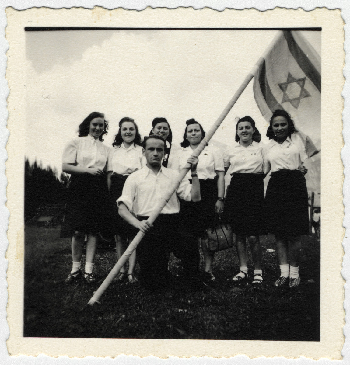 A group of teenage girls from the Chaim Nachman Bialik school in  Bad Gastein pose in front of a Zionist flag.

Among those pictured are Esther Ass (far right) and Chana Chamanovitch (second from the left).