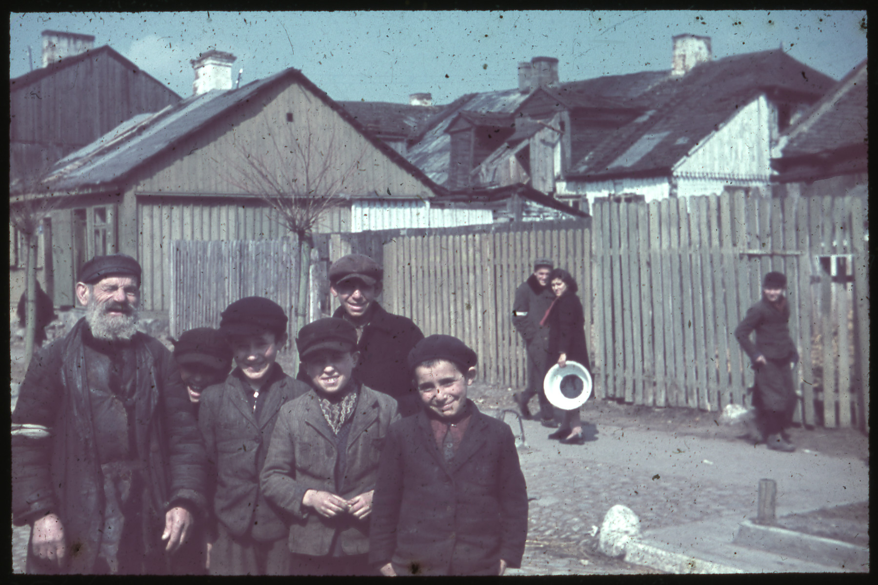 Group portrait of Jewish boys and an elderly man gathered together on a street.