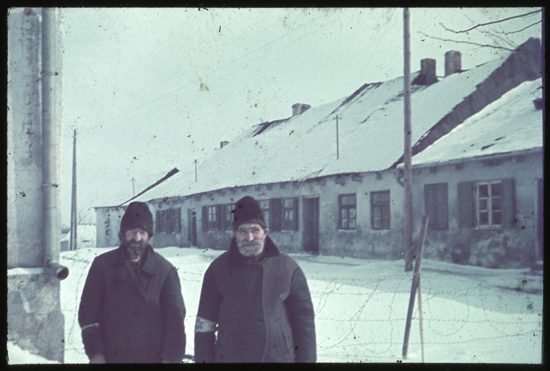 Close-up portrait of two Jewish men wearing beards and armbands on a snow-covered road.