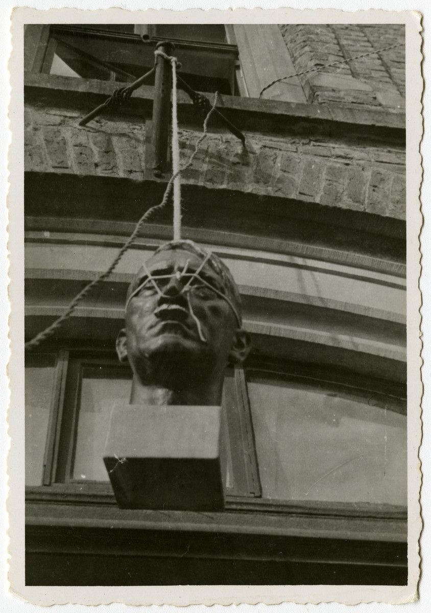 A bust of Adolf Hitler hangs outside of a building in Krofdorf, Germany. 

Original caption reads: March 1945 
What they should have done with him a long time ago. 
Krofdorf, Germany